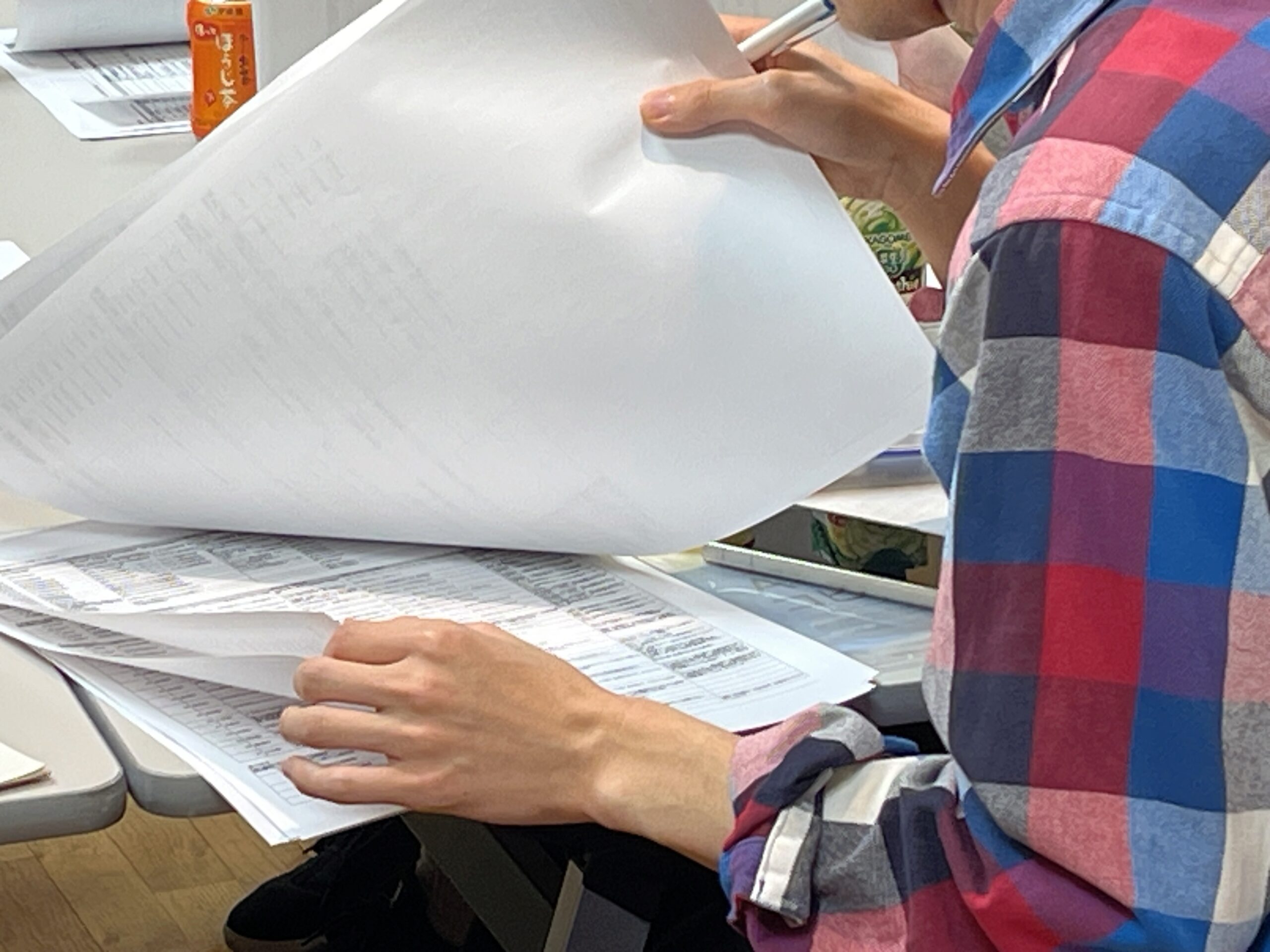 参加者がA3サイズの紙に印刷された資料をめくっている手元の写真
