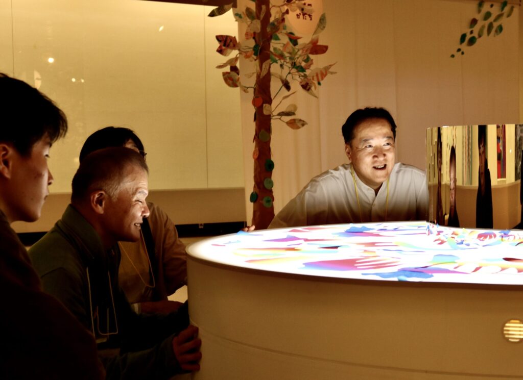 膝ぐらいの高さの作品を、参加者がしゃがんだ姿勢で眺めて微笑んでいる