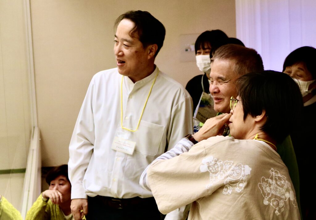 左にある作品を見ているグループの写真。中央に濱田さんの笑顔が見える。